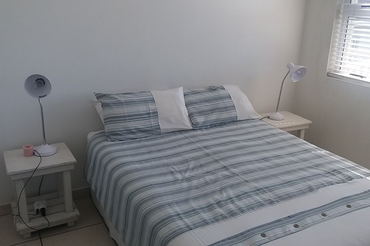 A functional bedroom featuring tiled flooring and venetian blinds, providing a neutral space ready for personalization.
