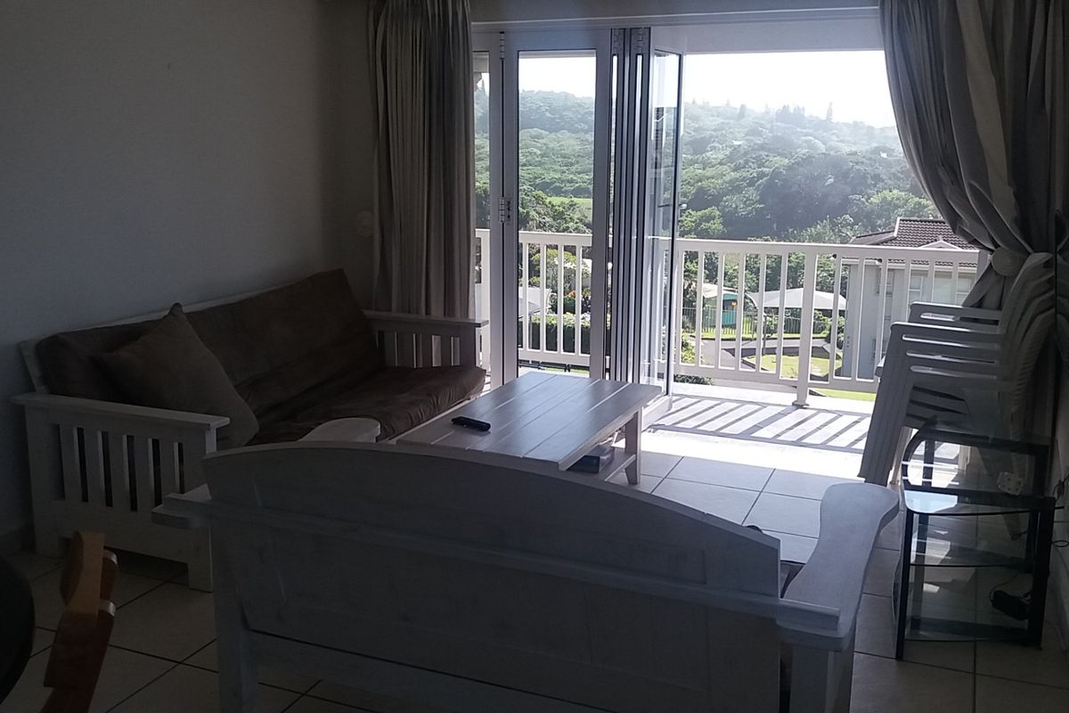 A living room featuring tiled flooring and large sliding glass doors that open onto a balcony with scenic views.