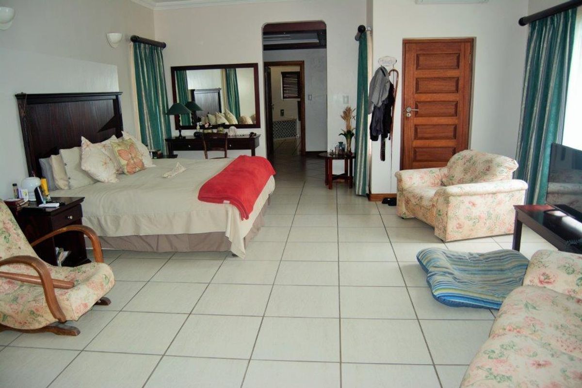 Spacious bedroom featuring neutral tiled flooring, a solid timber door, and an open archway leading to an adjoining space.