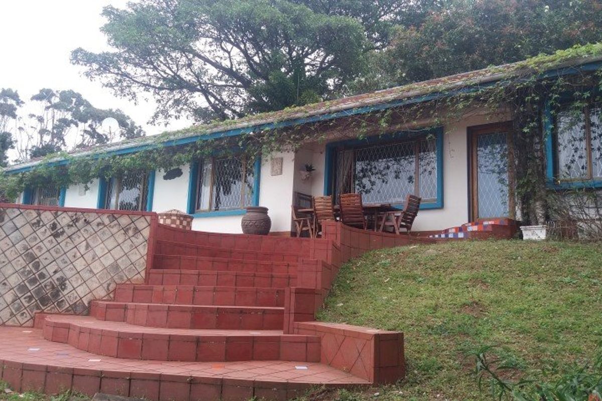 Rear exterior view of the house featuring a prominent tiled staircase, retaining walls, and large windows with decorative diamond-patterned glazing.