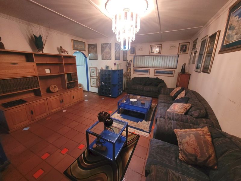 A living room featuring terracotta tiled flooring, a built-in wooden shelving unit, and a decorative ceiling rose with a central light fixture.