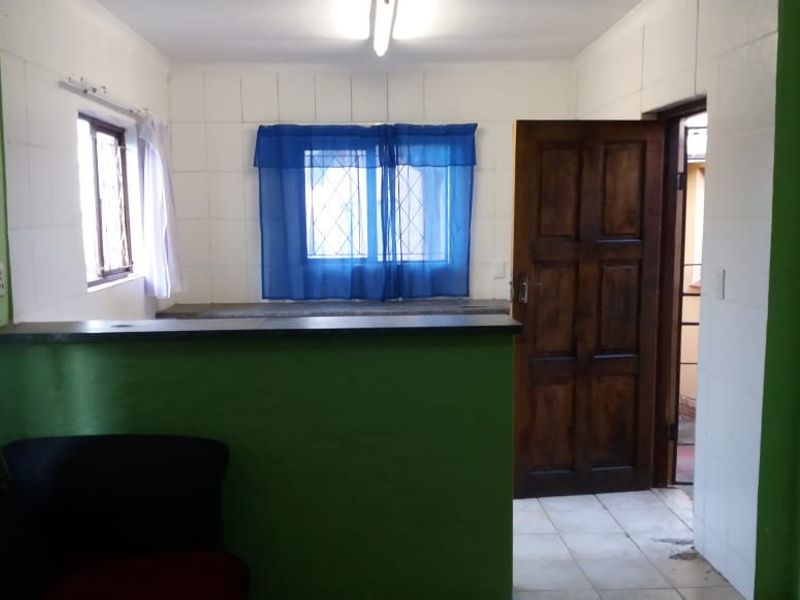 A functional kitchen area featuring tiled walls, a stone countertop, and a solid timber door leading to an exterior space.