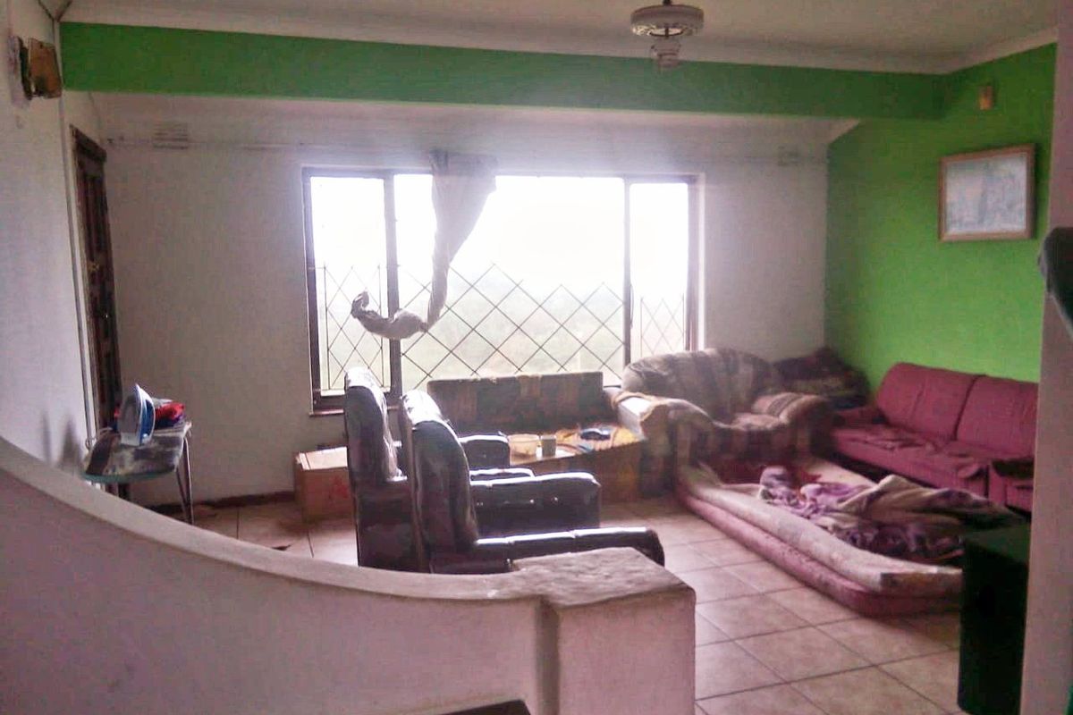 A living room featuring tiled flooring, a large window with security bars, and a ceiling fan, requiring cosmetic updates to improve its overall appeal.