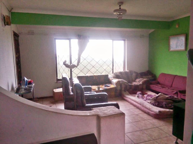 A living room featuring tiled flooring, a large window with security bars, and a ceiling fan, requiring cosmetic updates to improve its overall appeal.
