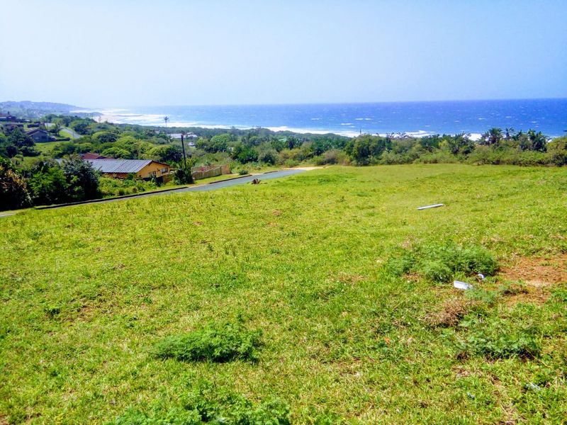 A vacant residential plot featuring a gentle slope and expansive, elevated views of the surrounding coastline and ocean.