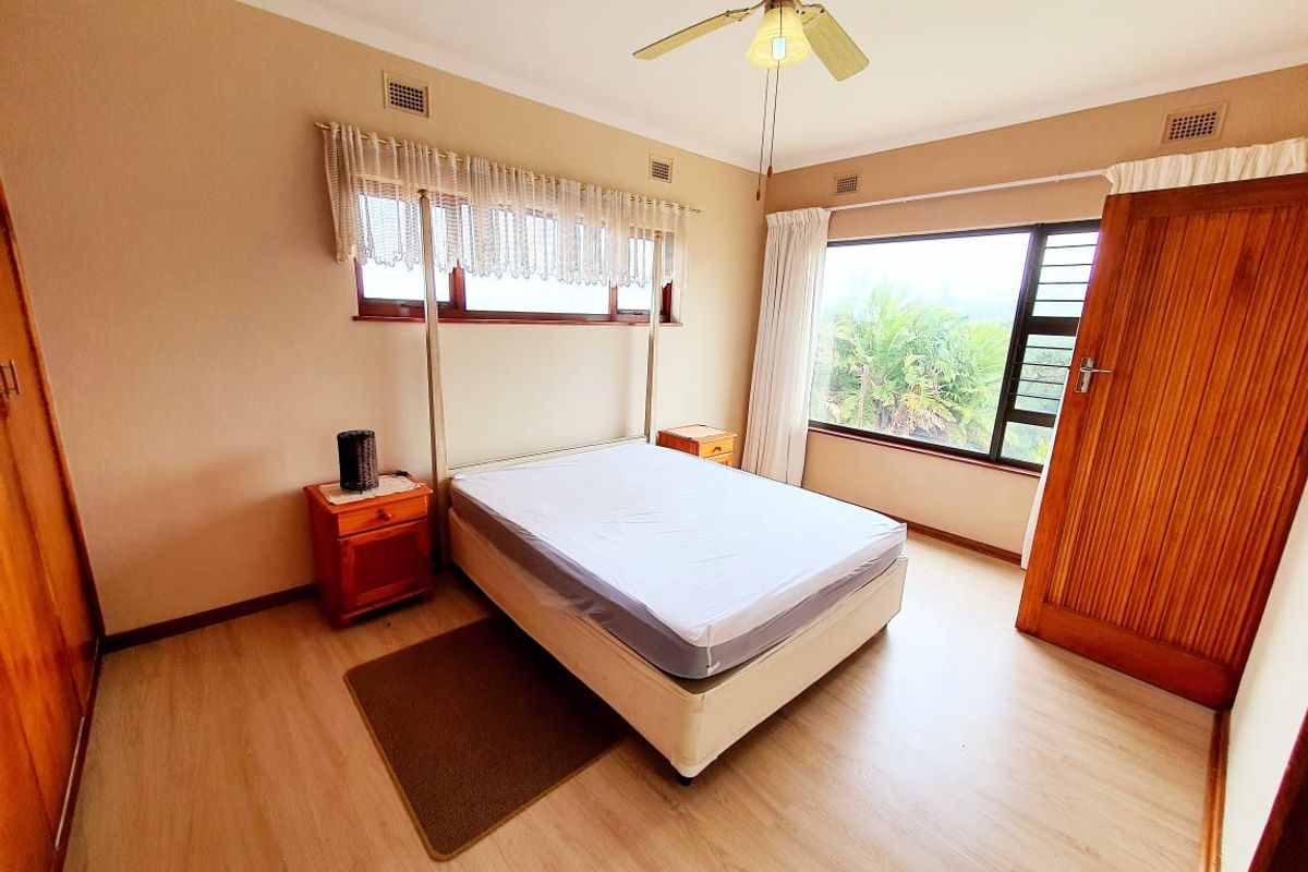 A well-lit bedroom featuring laminate flooring, built-in cupboards, and a ceiling fan, offering a comfortable and functional living space.