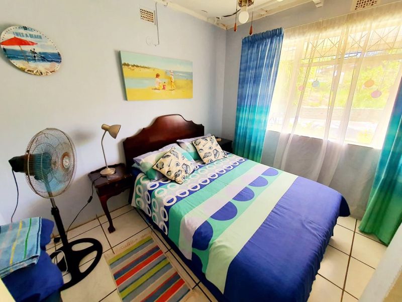 A functional bedroom featuring ceramic floor tiles, a window with security bars, and a ceiling vent, providing a comfortable and secure living space.