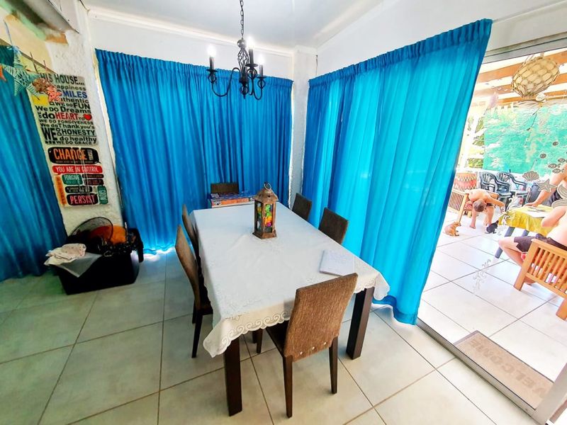 Dining room area featuring tiled flooring, a wrought iron chandelier, and large sliding glass doors providing access to the outdoor patio.