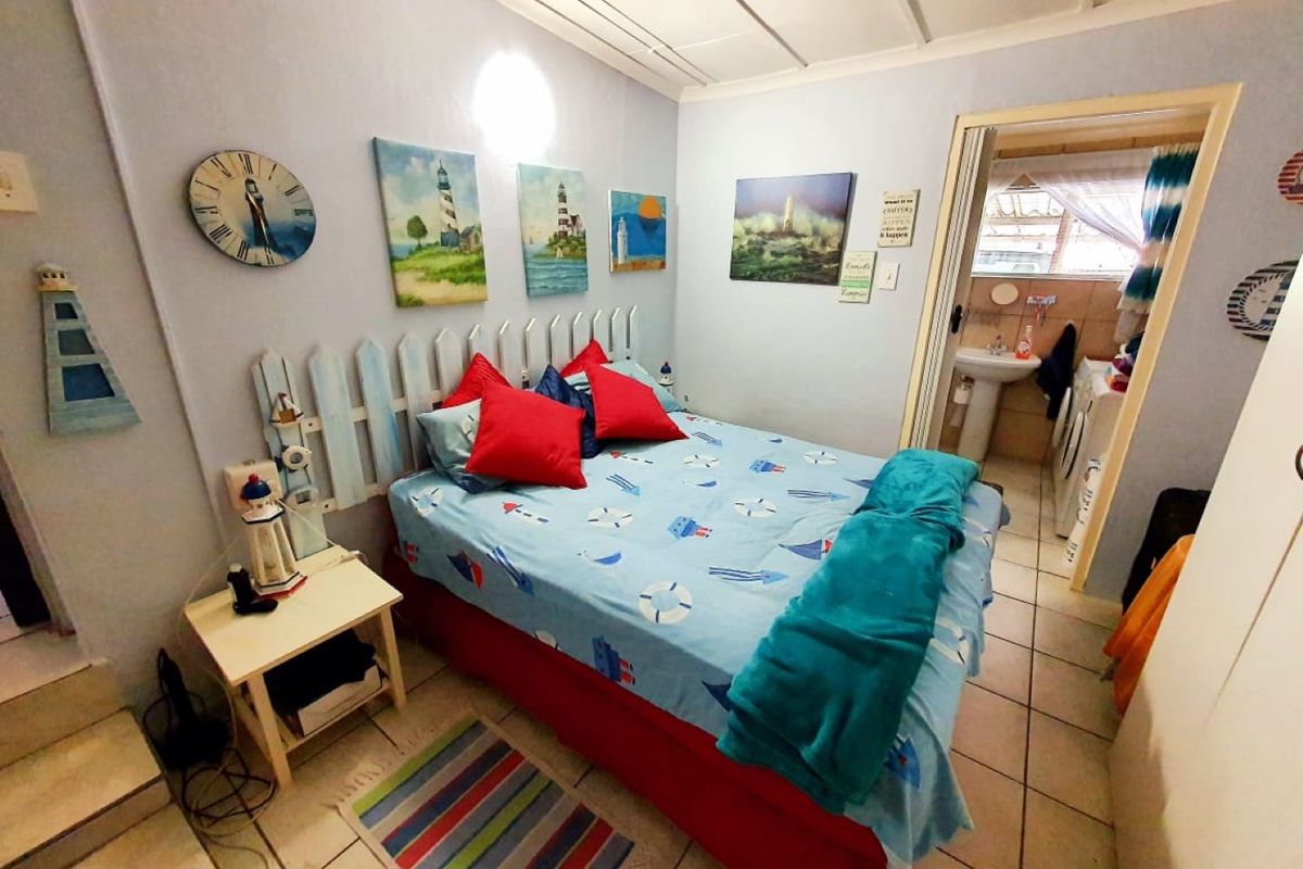 A bedroom featuring tiled flooring and an exposed beam ceiling, with direct access to an adjoining bathroom area.