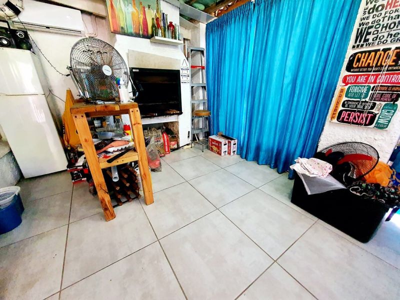 Covered patio area featuring a built-in braai, tiled flooring, and an installed air conditioning unit, offering potential for an improved outdoor entertainment space.