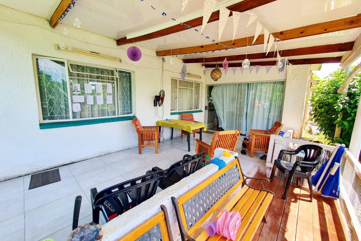 A covered patio area featuring tiled flooring, exposed timber beams, and sliding glass door access to the interior living space.