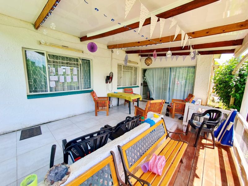 A covered patio area featuring tiled flooring, exposed timber beams, and sliding glass door access to the interior living space.