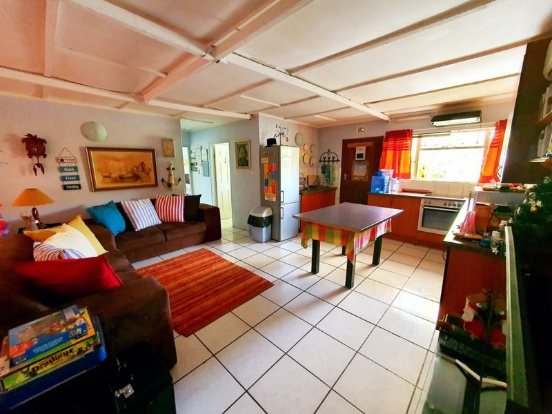 Open-plan living and kitchen area featuring tiled flooring, exposed beam ceilings, and functional built-in cabinetry with integrated oven and hob.