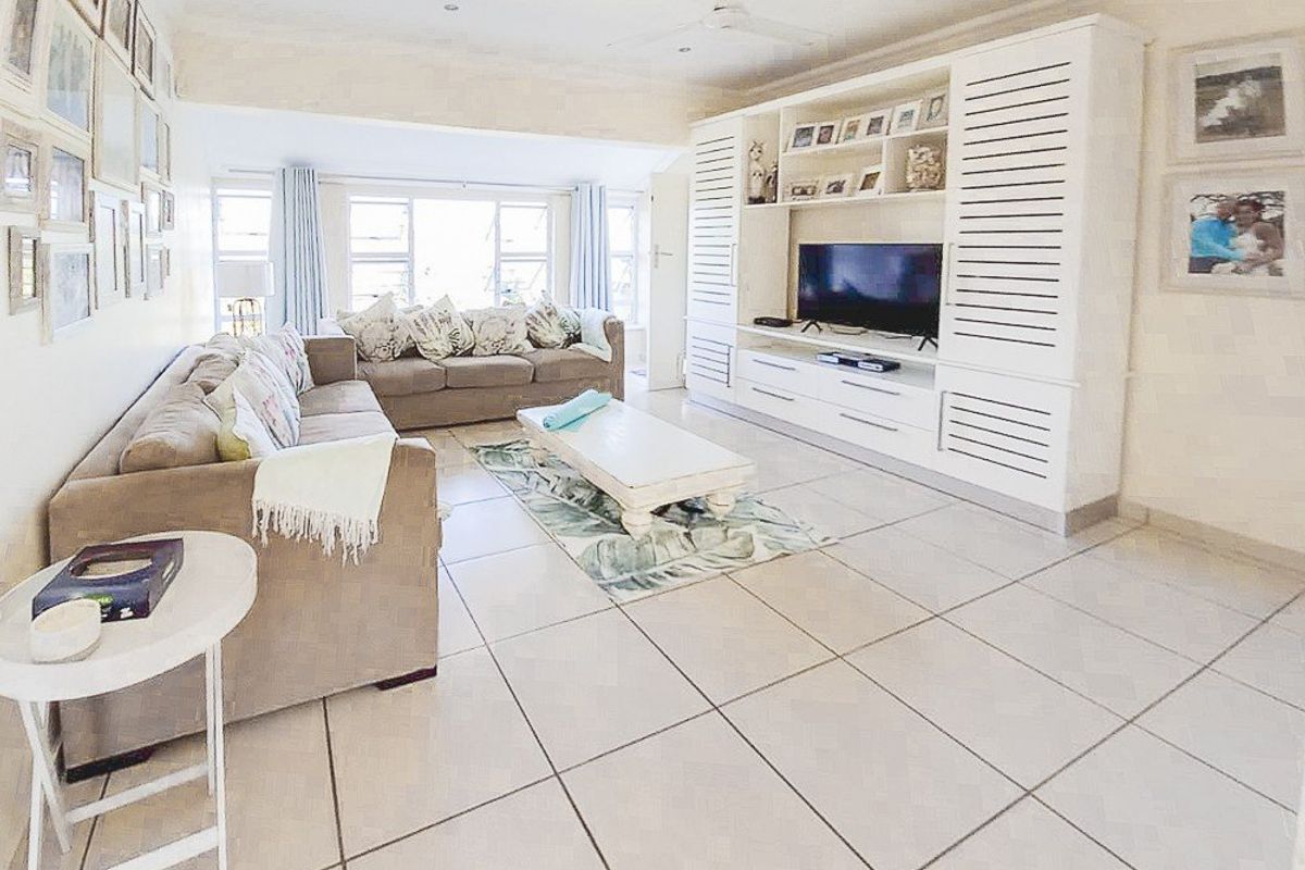 Spacious living room featuring large format floor tiles, a ceiling fan, and extensive built-in cabinetry for media and storage.