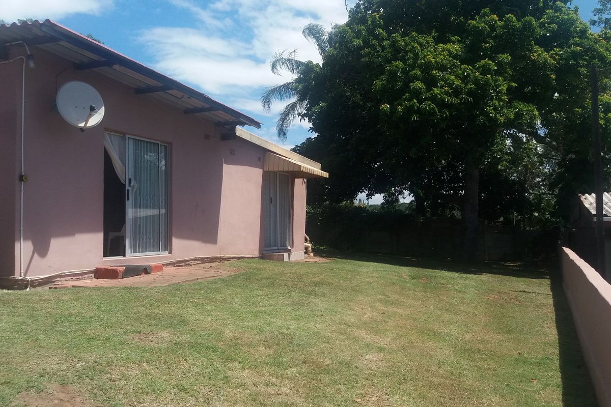 Rear view of the house featuring a lawn, sliding glass doors, and a boundary wall.