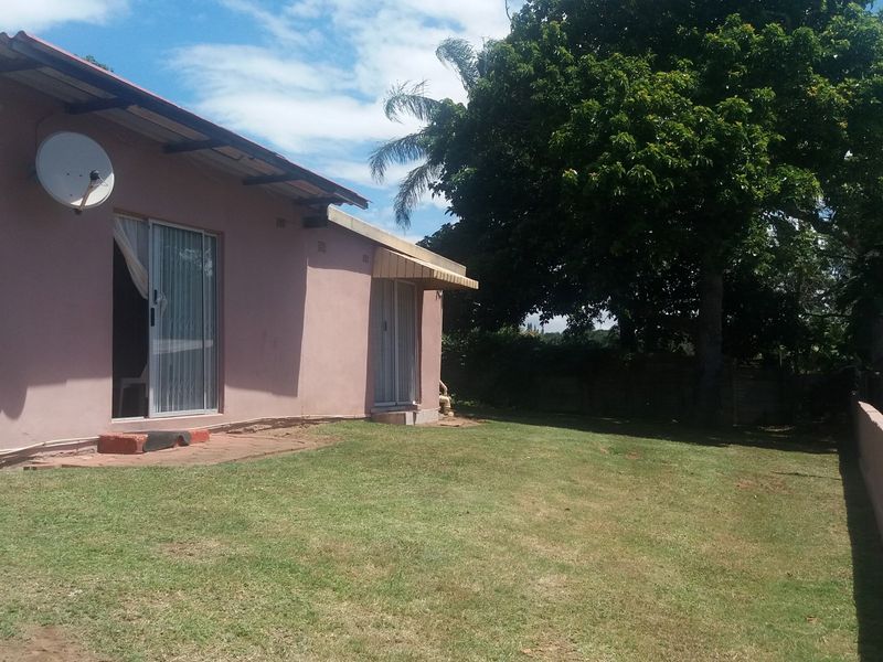 Rear view of the house featuring a lawn, sliding glass doors, and a boundary wall.