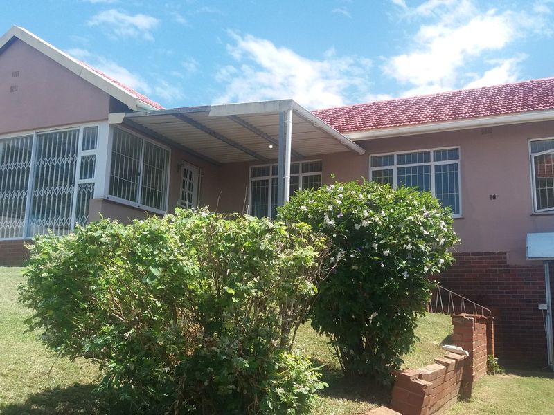 Front elevation of a single-story house featuring a tiled roof, covered patio area, and security-fitted windows, set within a landscaped garden.