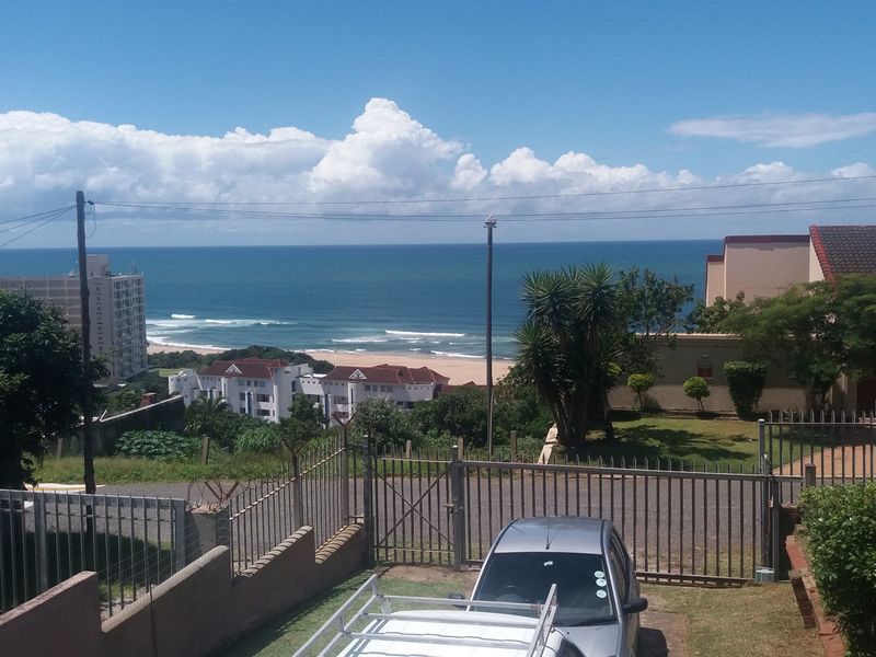 Elevated coastal view overlooking the ocean, surrounding residential properties, and landscaped grounds with secure perimeter fencing.