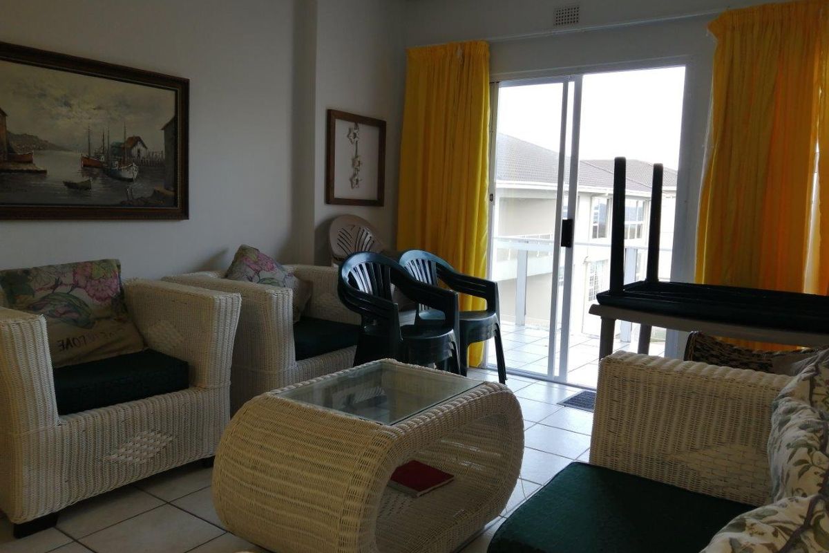 A living room area featuring tiled flooring and sliding glass doors that provide access to an outdoor balcony.