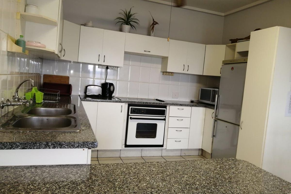 A functional kitchen featuring white cabinetry, granite-look countertops, a double basin sink, and a built-in oven with an extractor fan.