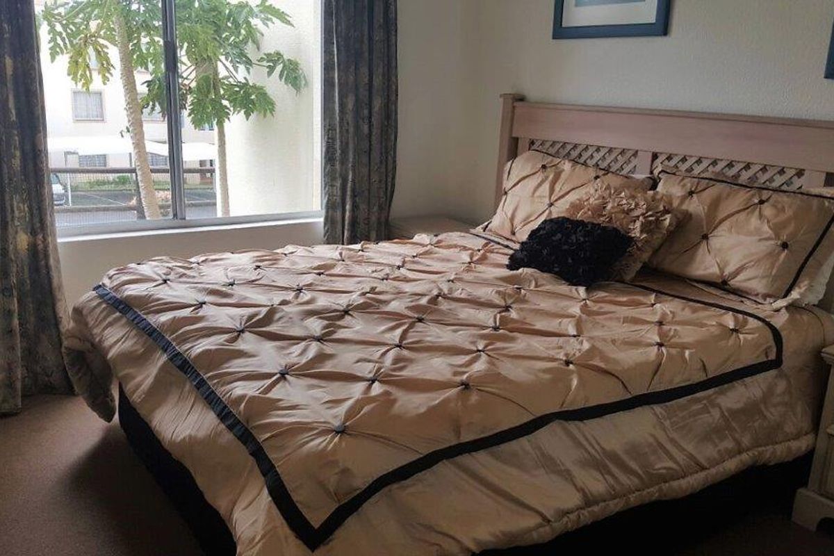 A comfortable bedroom featuring carpeted flooring and a large sliding glass window that provides natural light.