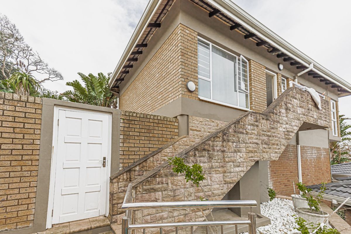 Exterior view of the property featuring a stone-clad staircase, brick facade, and a secure side entrance door.