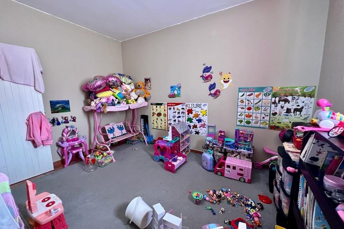 A standard bedroom featuring neutral wall paint, carpeted flooring, and a built-in cupboard, currently utilized as a children's play area.