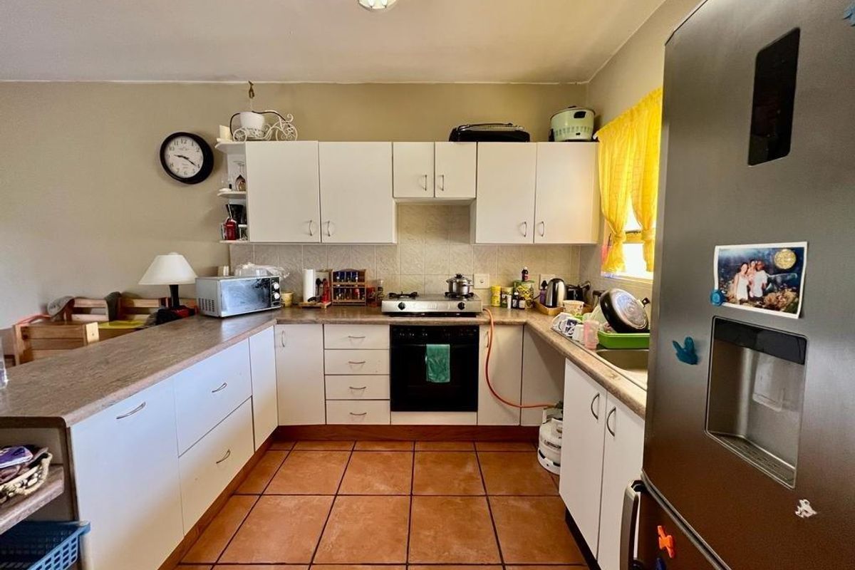 A functional kitchen featuring white cabinetry, laminate countertops, a built-in oven with gas hob, and tiled flooring.