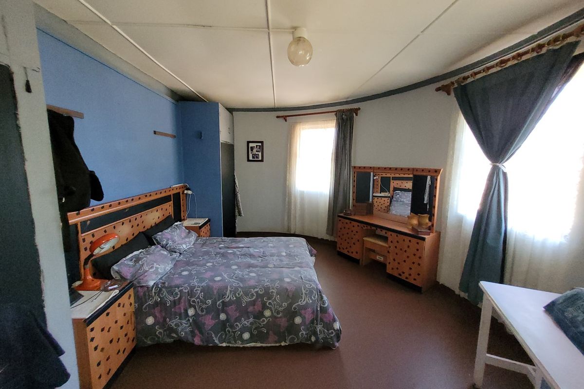 A spacious bedroom featuring a curved wall design, built-in storage, and large windows allowing for natural light.