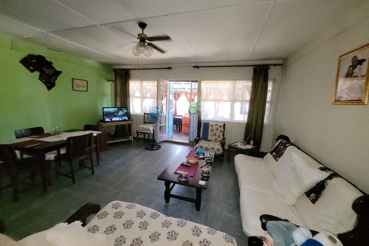 A living room area featuring tiled flooring, a ceiling fan, and access to an outdoor space through french doors.