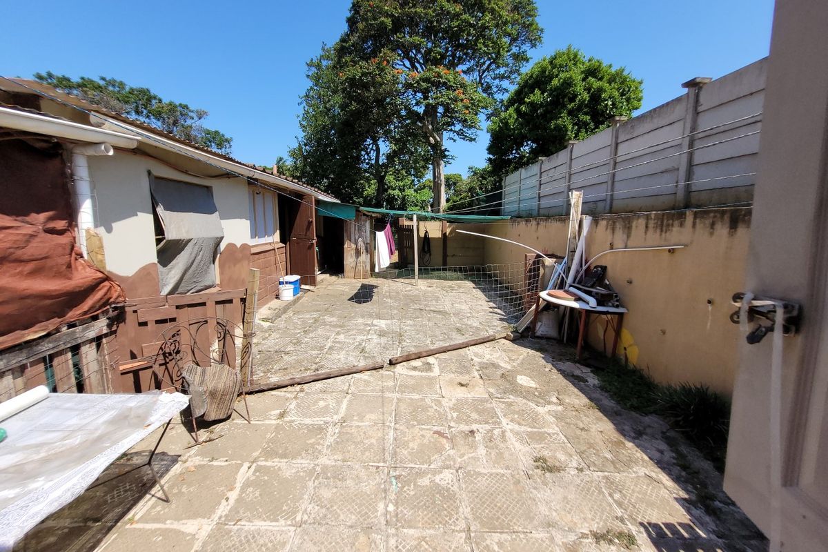 A rear exterior area featuring a paved patio, boundary walls, and a washing line, requiring maintenance and cosmetic updates to improve the outdoor space.