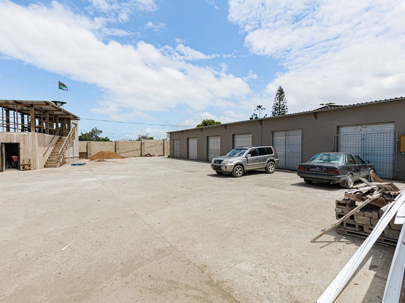 Spacious industrial yard featuring multiple roller shutter doors, a concrete surface, and a raised observation deck with external staircase access.
