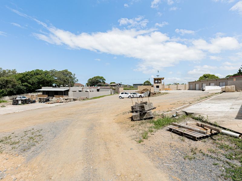 Wide-angle view of an industrial property site featuring warehouse units, a security guard tower, and an unpaved yard area.