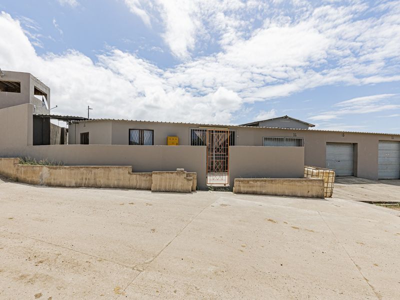 Front exterior view of an industrial property featuring multiple roller shutter garage doors, a secure gated entrance, and a concrete driveway.