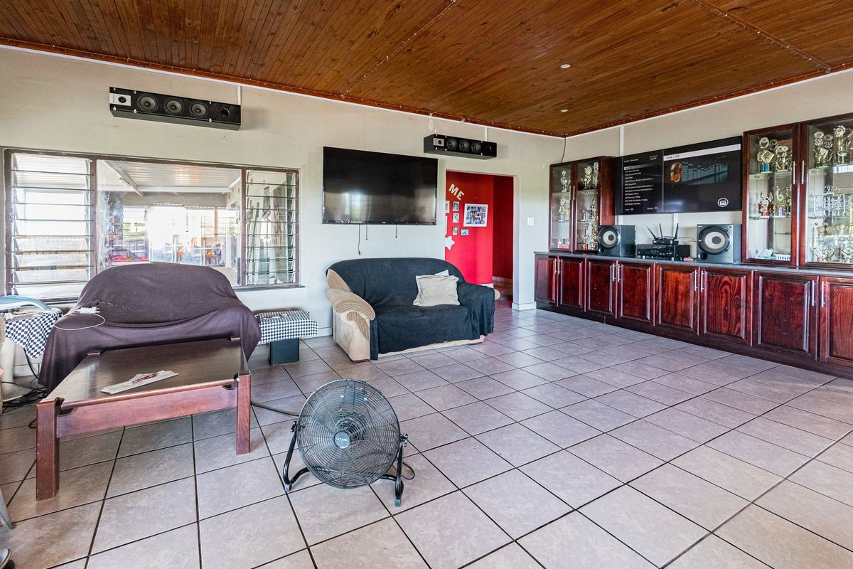Spacious living area featuring a timber-clad ceiling, tiled flooring, and extensive built-in cabinetry, offering a functional layout with natural light through louvre windows.