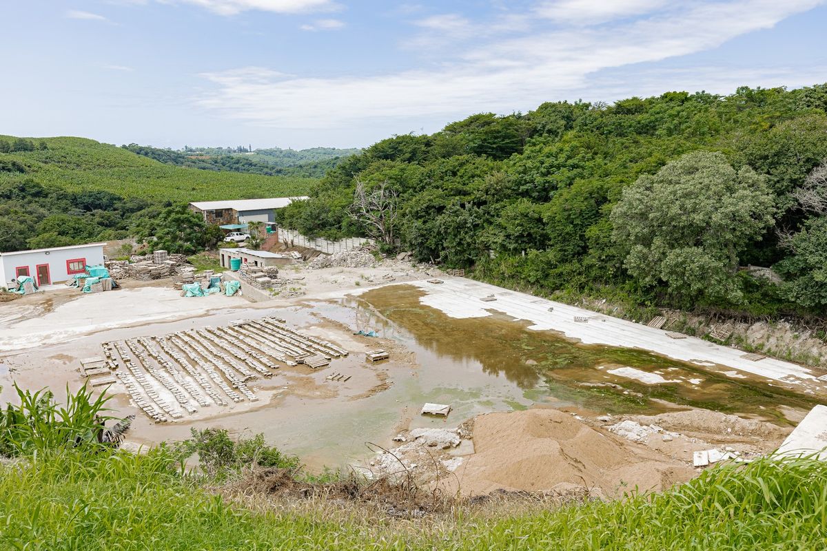 Aerial view of an industrial site featuring a large concrete yard, storage areas, and surrounding natural landscape.
