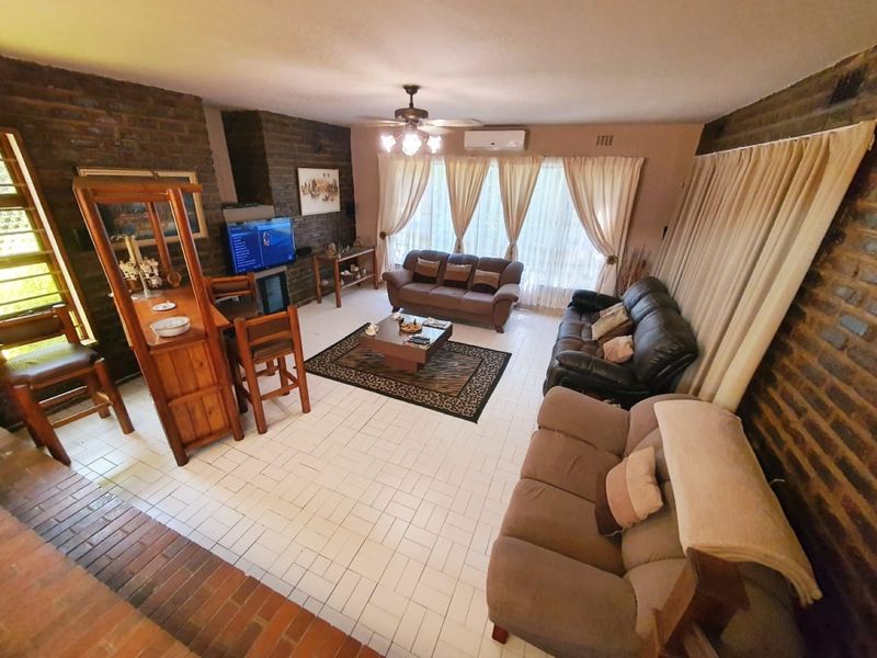 Spacious living room featuring exposed brick walls, ceramic tile flooring, and a ceiling fan, offering a comfortable and functional layout.