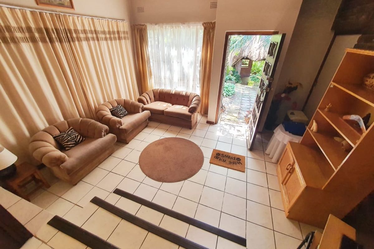A living room featuring ceramic tiled flooring, a stepped floor transition, and direct access to an outdoor garden area through an external door.