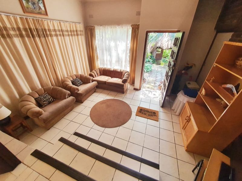 A living room featuring ceramic tiled flooring, a stepped floor transition, and direct access to an outdoor garden area through an external door.