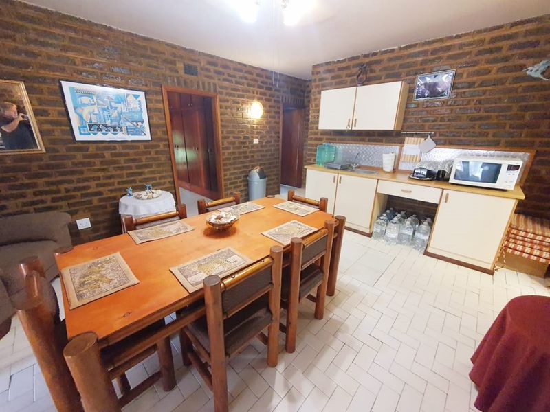 Open-plan living and kitchen area featuring exposed brick walls, tiled flooring, and functional built-in kitchen cabinetry with a sink.