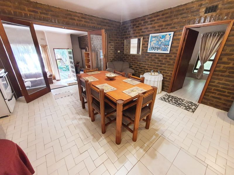 Dining area featuring exposed brick walls and ceramic tile flooring, with direct access to an outdoor patio through glass panelled doors.