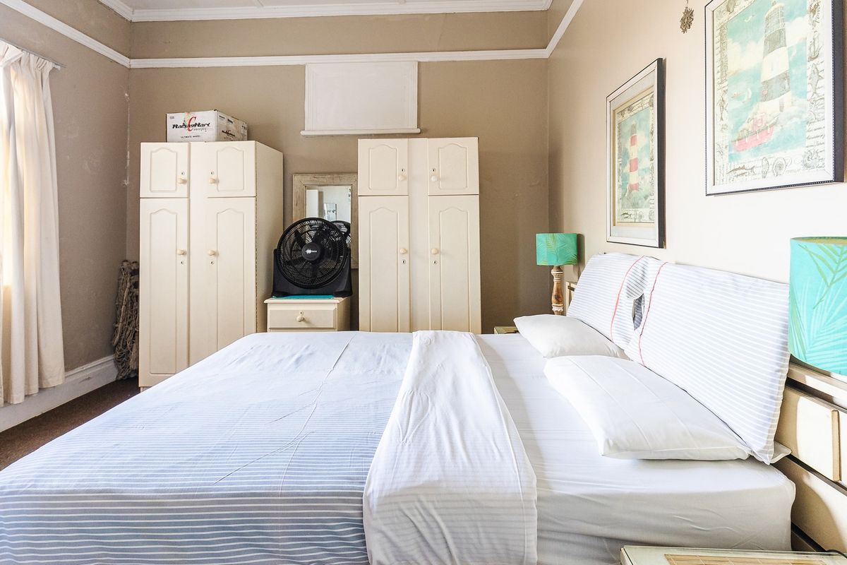 A bedroom featuring neutral wall tones, crown molding, and baseboards, providing a functional space ready for modern updates.