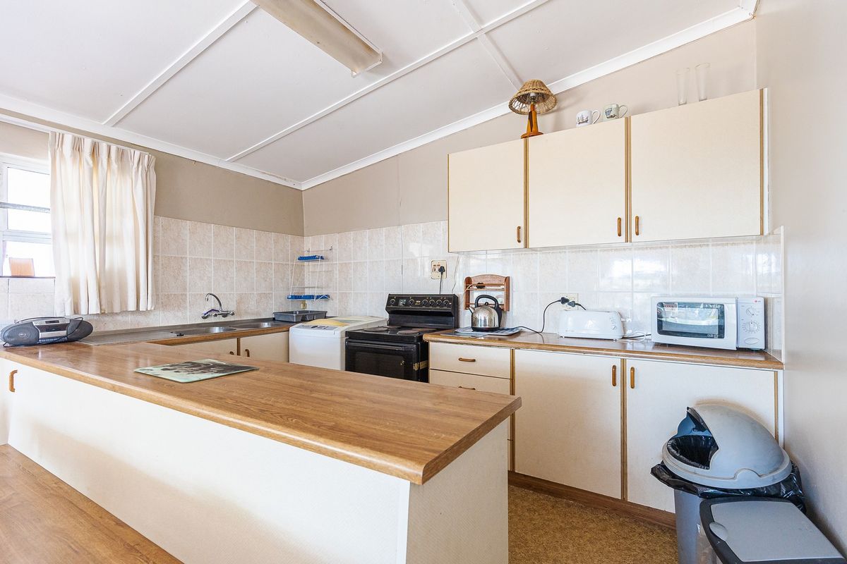 A functional kitchen featuring laminate countertops, tiled backsplash, and ample built-in cabinetry, offering a dated aesthetic ready for modernization.