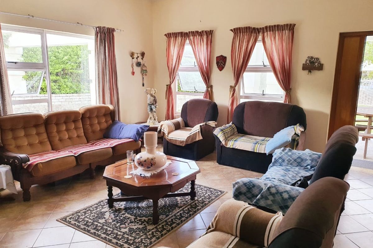 A spacious living room featuring tiled flooring and large aluminium-framed windows that provide ample natural light.