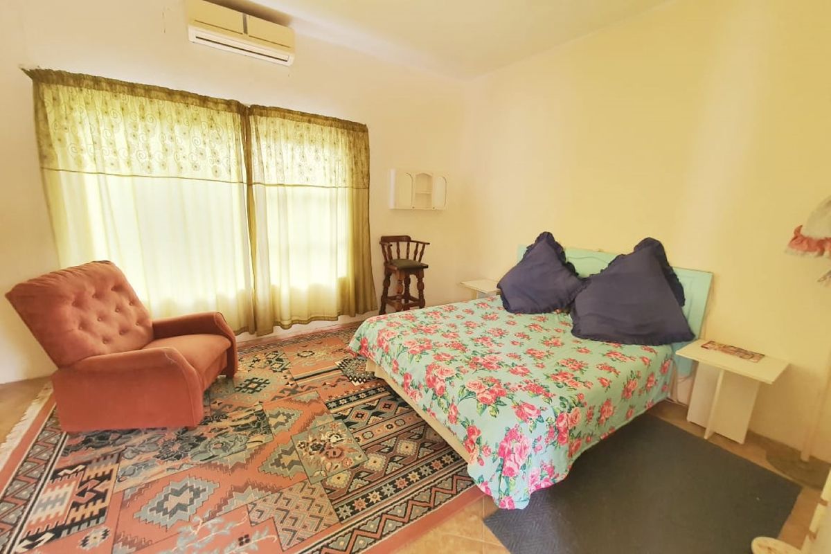 A bedroom featuring tiled flooring and a wall-mounted split-system air conditioning unit.