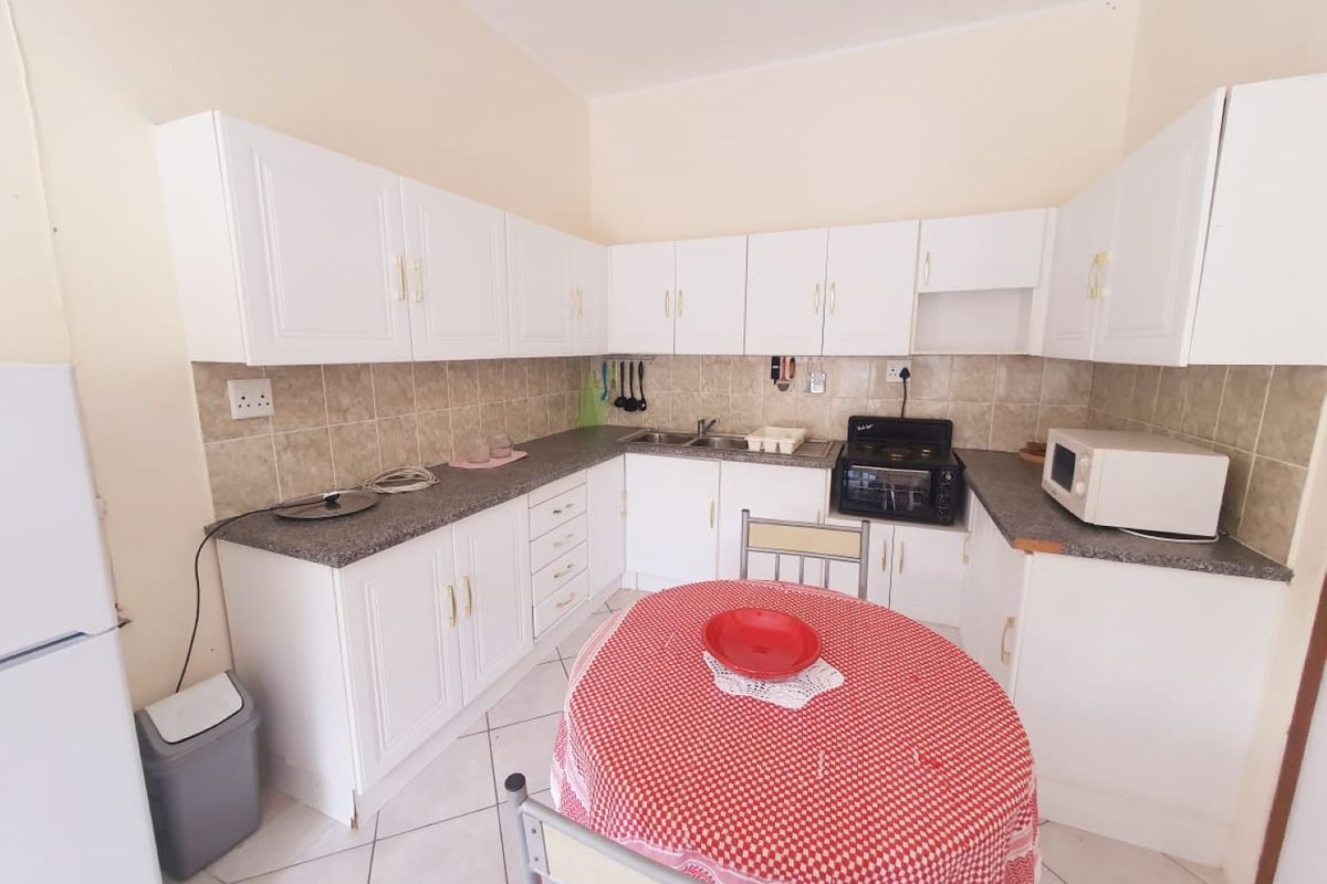 A functional kitchen featuring white cabinetry, laminate countertops, tiled backsplash, and built-in oven, providing a practical layout for daily meal preparation.