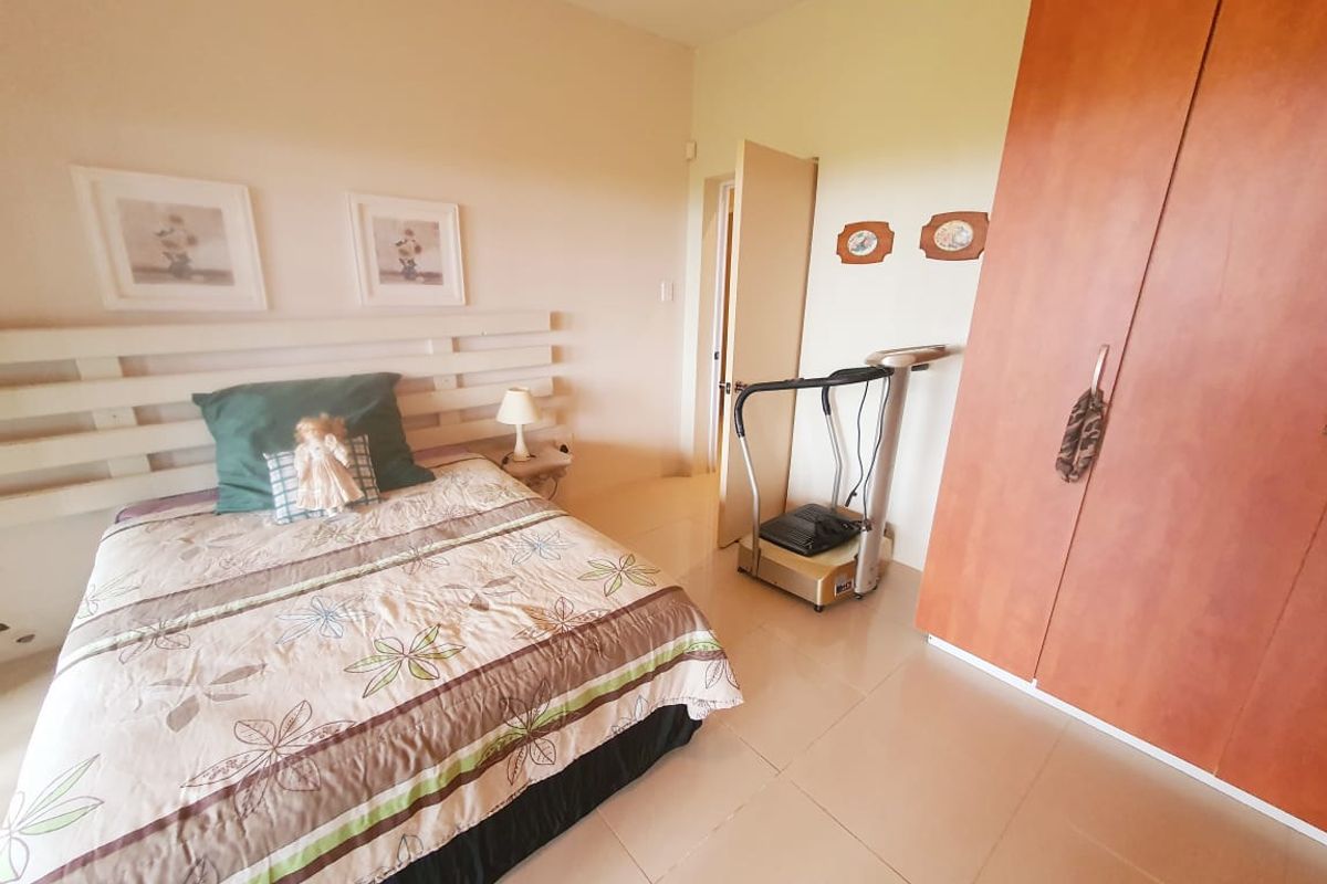 A bedroom featuring tiled flooring and a built-in wooden wardrobe, providing functional storage space.
