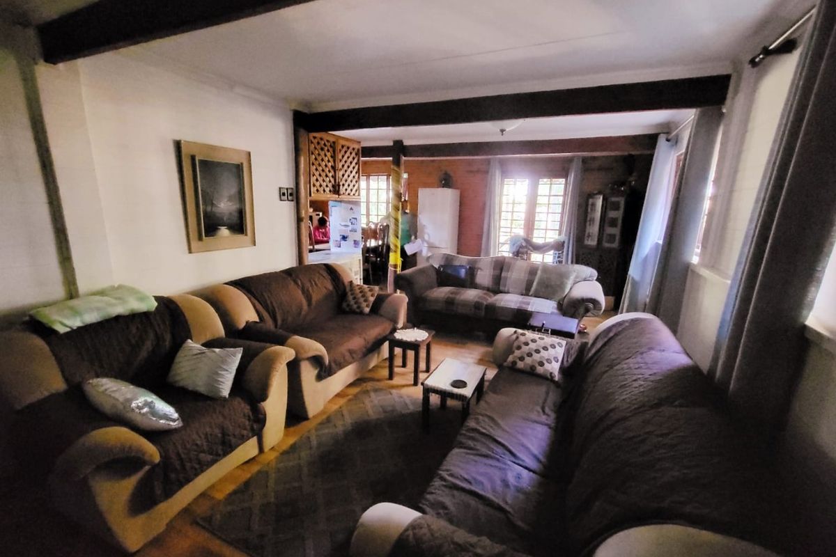 A cozy living room featuring exposed ceiling beams, timber window frames, and hardwood flooring, offering a warm and traditional atmosphere.