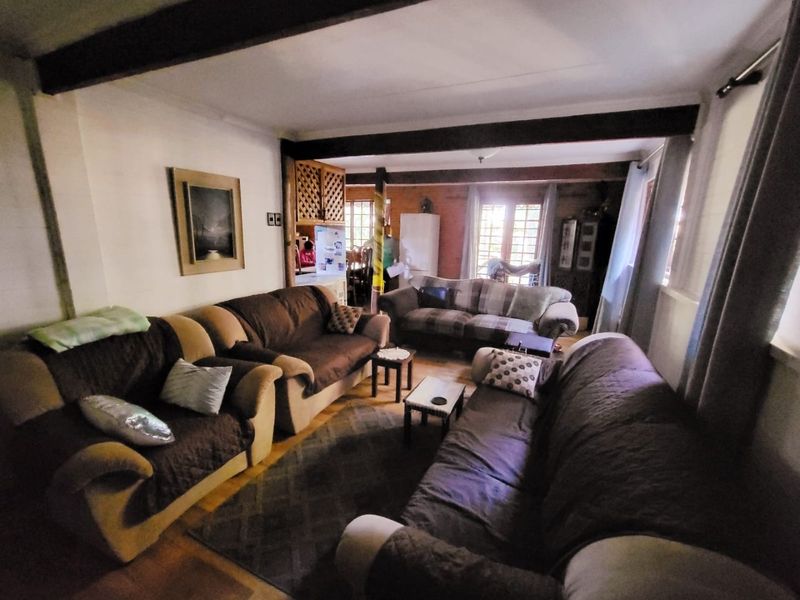 A cozy living room featuring exposed ceiling beams, timber window frames, and hardwood flooring, offering a warm and traditional atmosphere.