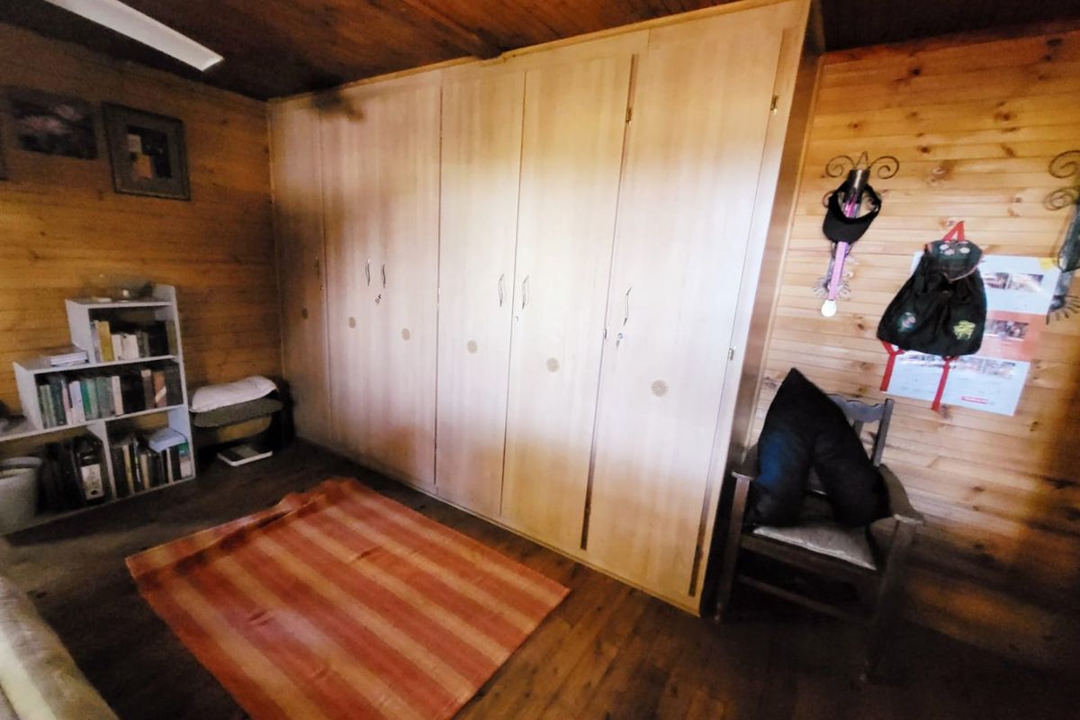 Bedroom featuring extensive built-in cupboards, natural timber wall paneling, and timber ceiling finishes.